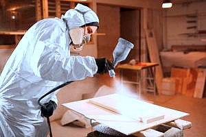 a contractor spraying a piece of fire retardant plywood