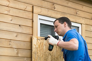 a contractor covering a window with plywood