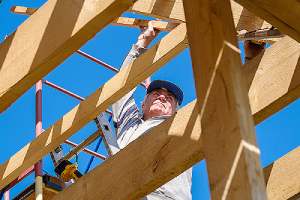 Construction worker working on a wooden frame. Buying materials like lumber from wholesale suppliers can be beneficial
