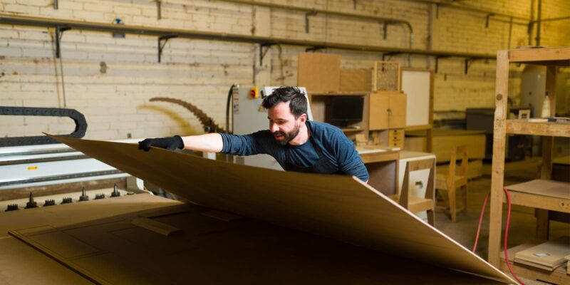 a construction worker picking up treated plywood for his project